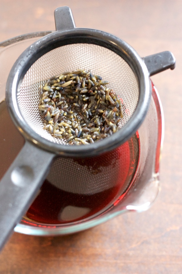 lavender buds in strainer over contained liquid